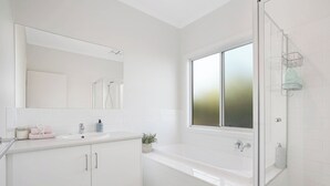 A modern bathroom with a large mirror, a bathtub, and a shower area. - Beach by the Dunes: Relaxing, contemporary beach house, walk to beach and river (Goolwa Beach)