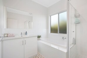 A modern bathroom with a large mirror, a bathtub, and a shower area. - Beach by the Dunes: Relaxing, contemporary beach house, walk to beach and river (Goolwa Beach)