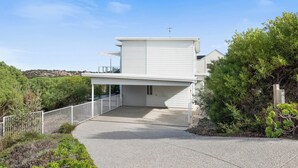 Une maison moderne à deux étages, dotée d’une allée couverte et d’une cour clôturée.