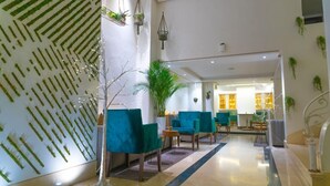 Un vestíbulo moderno con sillas color turquesa, un diseño de pared con motivos y plantas de interior.