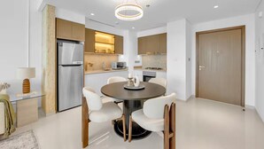 A modern kitchen with a central island, stainless steel appliances, and a dining area with a round table and chairs. - Elegant 1BR at Emmar Beachfront (Dubai)