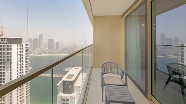 A balcony with a view of a city skyline and a body of water. - Elegant 1BR at Emmar Beachfront (Dubai)