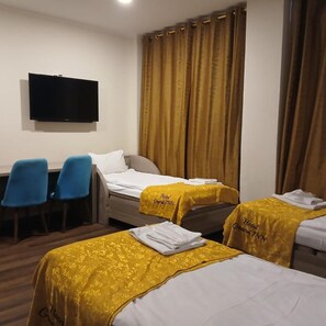 A hotel room with two beds, a desk, and a television. - Hotel Grand Inn (Berlin)