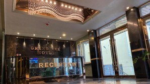 A reception area with a chandelier, a reception desk, and a marble floor with a geometric pattern. - Hotel Grand Inn (Berlin)