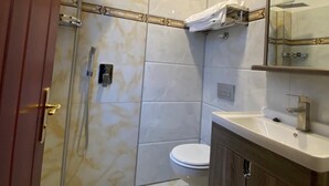 A bathroom with a shower, toilet, and sink. - Hotel Grand Inn (Berlin)