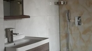 A bathroom with a sink, mirror, shower, and decorative wall tiles. - Hotel Grand Inn (Berlin)