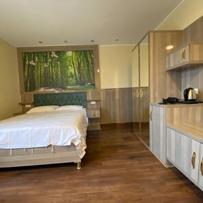 A bedroom with a bed, a wardrobe, a mirror, and a painting of a forest. - Hotel Grand Inn (Berlin)