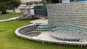 A swimming pool with a mosaic design, surrounded by a stone wall and a grassy area. - Hotel Grand Inn (Berlin)