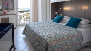 A hotel room with a bed, a desk, a chair, a balcony, and a view of the outdoors. - Hotel Sole (Cattolica)