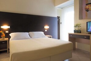 A hotel room with a bed, bedside tables, a desk, a television, and a window with curtains. - Hotel Sole (Cattolica)