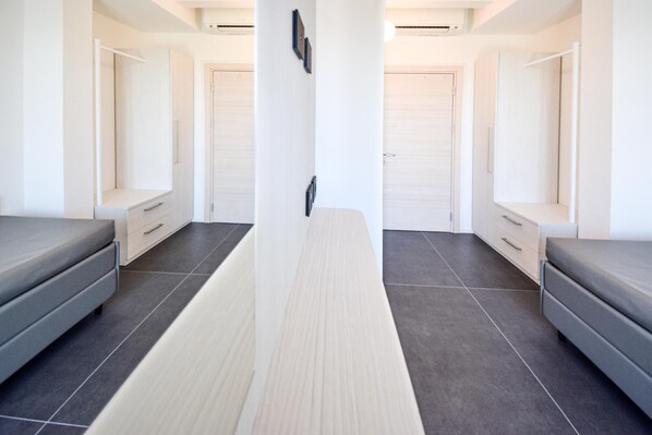 A modern hotel room with a central bed, two bedside tables, a large mirror, and a wardrobe. - Hotel Giulio Cesare (Cattolica)