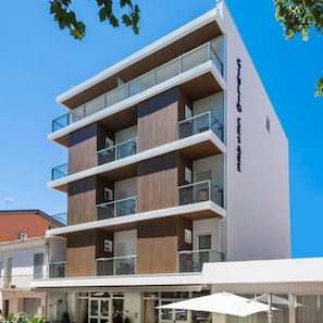Ein mehrstöckiges Hotel mit Balkonen, einer schlichten Fassade und blauem Himmel.