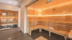 Una sauna con bancos de madera y paredes de vidrio, un reloj en la pared y techo de madera.