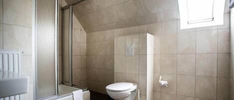 A modern bathroom with a shower, toilet, and a window providing natural light.