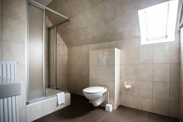 Un baño moderno con ducha, inodoro y ventana que proporciona luz natural.