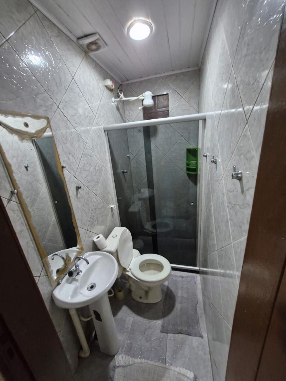 Casa de banho compacta com sanita, lavatório e cabine de duche.