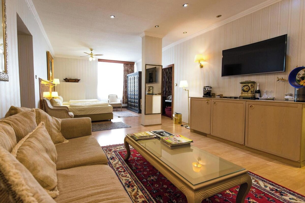 Una habitación de hotel con sofá, mesa de centro, televisión y zona de cocina.