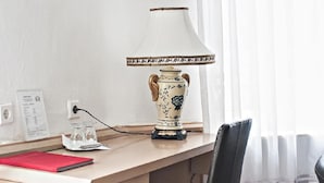Un escritorio con una lámpara, una silla, una carpeta roja y un vaso.
