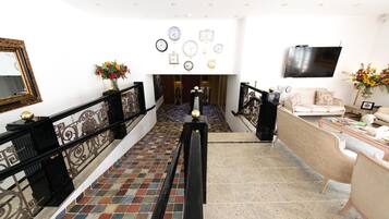 Eine Hotelhalle mit Treppe, einer Rezeption und einer Wand mit Uhren.