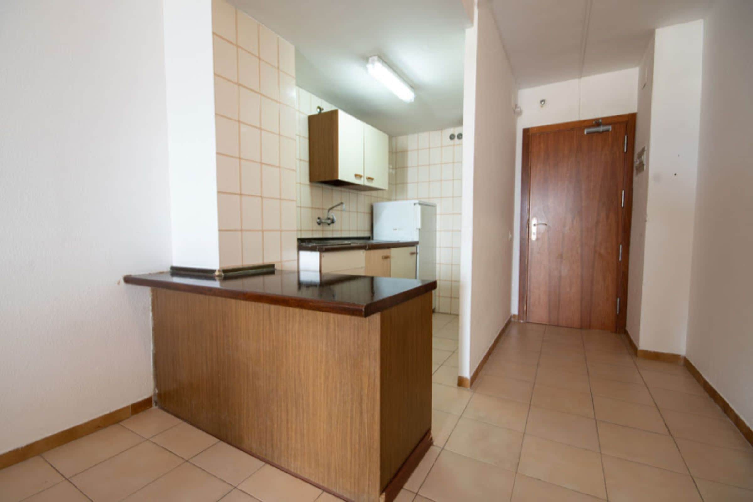 A kitchen with a wooden countertop, white cabinets, and a tiled backsplash.
