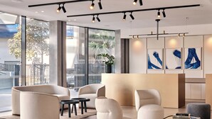 Un vestíbulo moderno con ventanas amplias, una recepción y asientos contemporáneos.