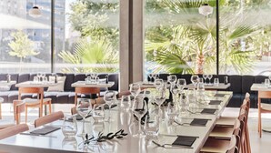 Un restaurante con una larga mesa de comedor dispuesta con copas de vino y cubiertos, rodeada de sillas y un sofá.
