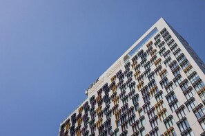 Ein Hochhaus mit moderner Architektur, gekennzeichnet durch ein Fenstergitter und eine auffällige Beschilderung oben.