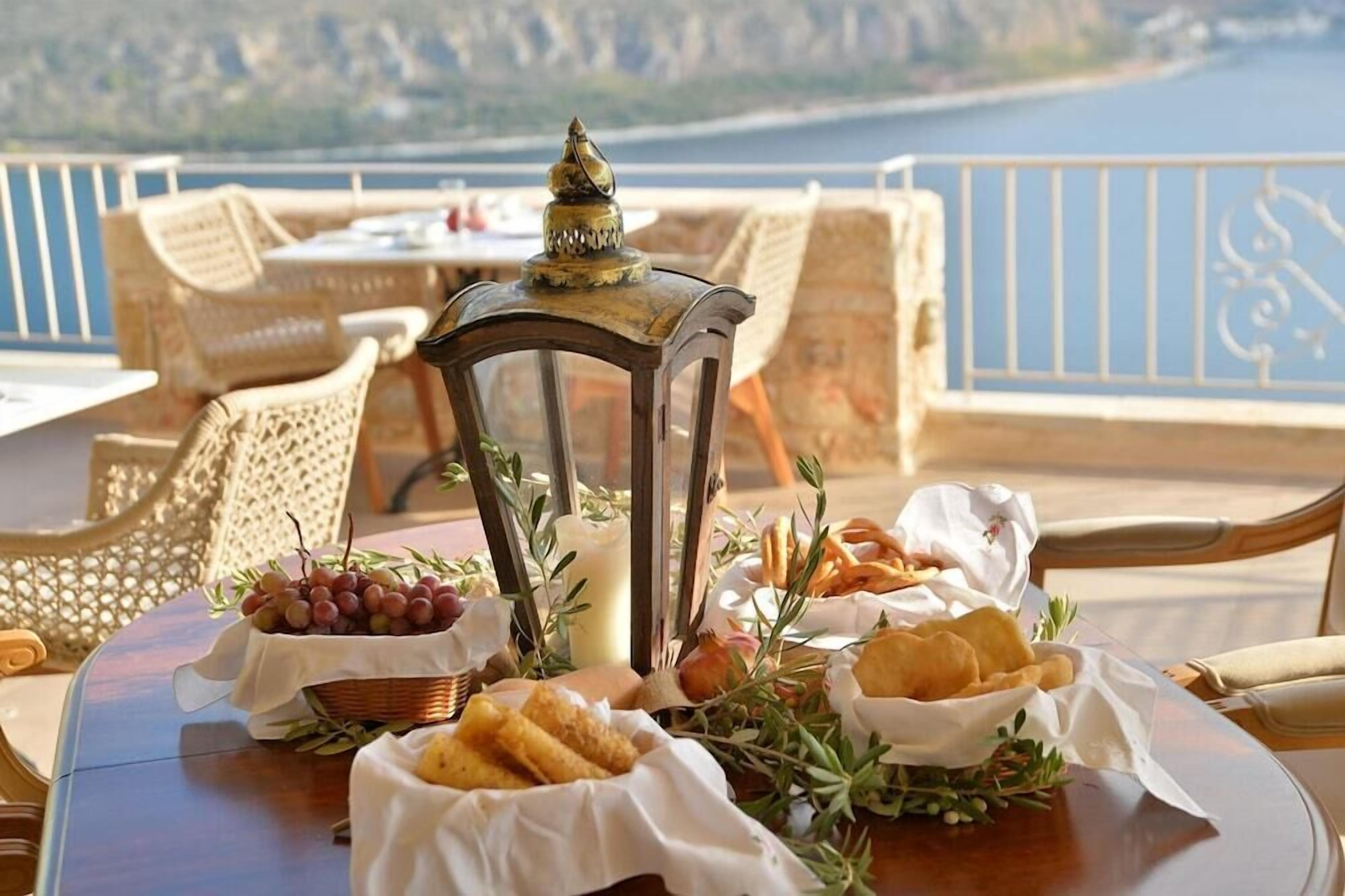 A table set with food and a lantern, overlooking a scenic view.