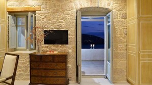 Interior de pared de piedra con un televisor de pantalla plana, armarios de madera y vista a través de una puerta abierta.