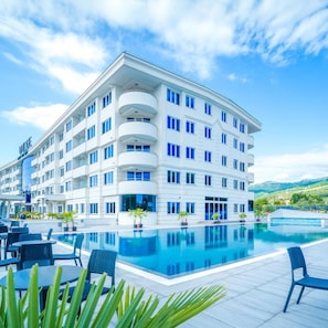 A multi-story hotel with a pool, outdoor seating, and a mountainous backdrop. - Unique Resort & Spa (Ohrid)