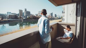 A modern building with a balcony overlooking a river and cityscape. - Lazuli Hiroshima Hotel & Lounge (Hiroshima)