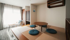 A modern hotel room with tatami mats, a round table, a sofa, and a view of the outdoors. - Lazuli Hiroshima Hotel & Lounge (Hiroshima)