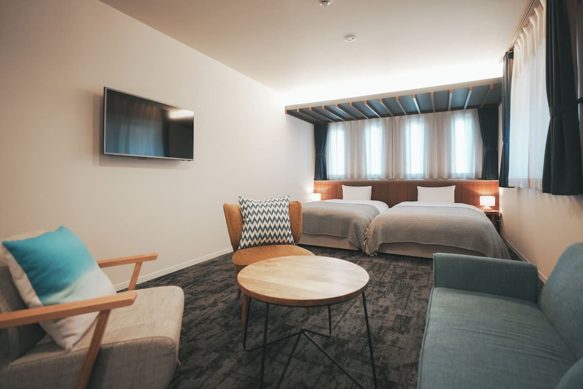 Une chambre d’hôtel comprenant un lit, deux tables de chevet, un téléviseur, un canapé et un fauteuil.