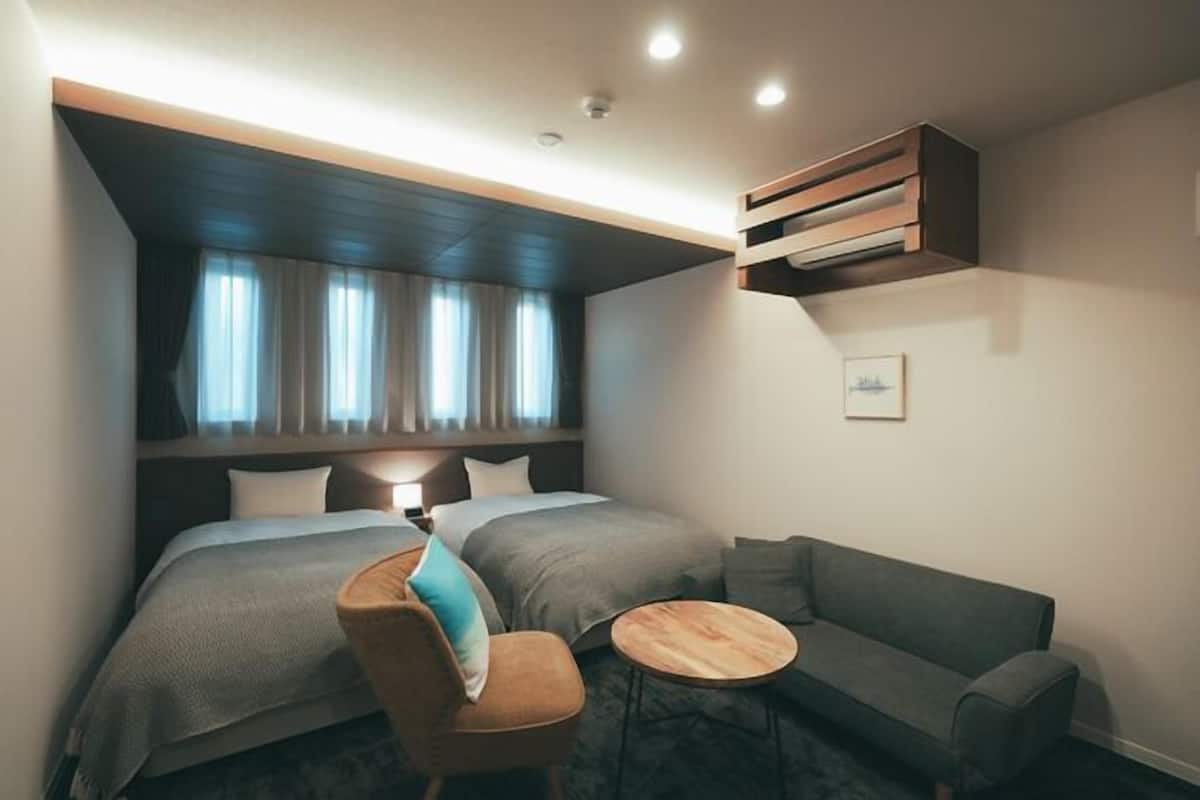 Une chambre d’hôtel avec un lit, deux tables de chevet, un canapé et une petite table ronde.