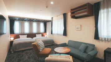 Une chambre d’hôtel avec deux lits, un canapé, une chaise, une petite table et un radiateur.