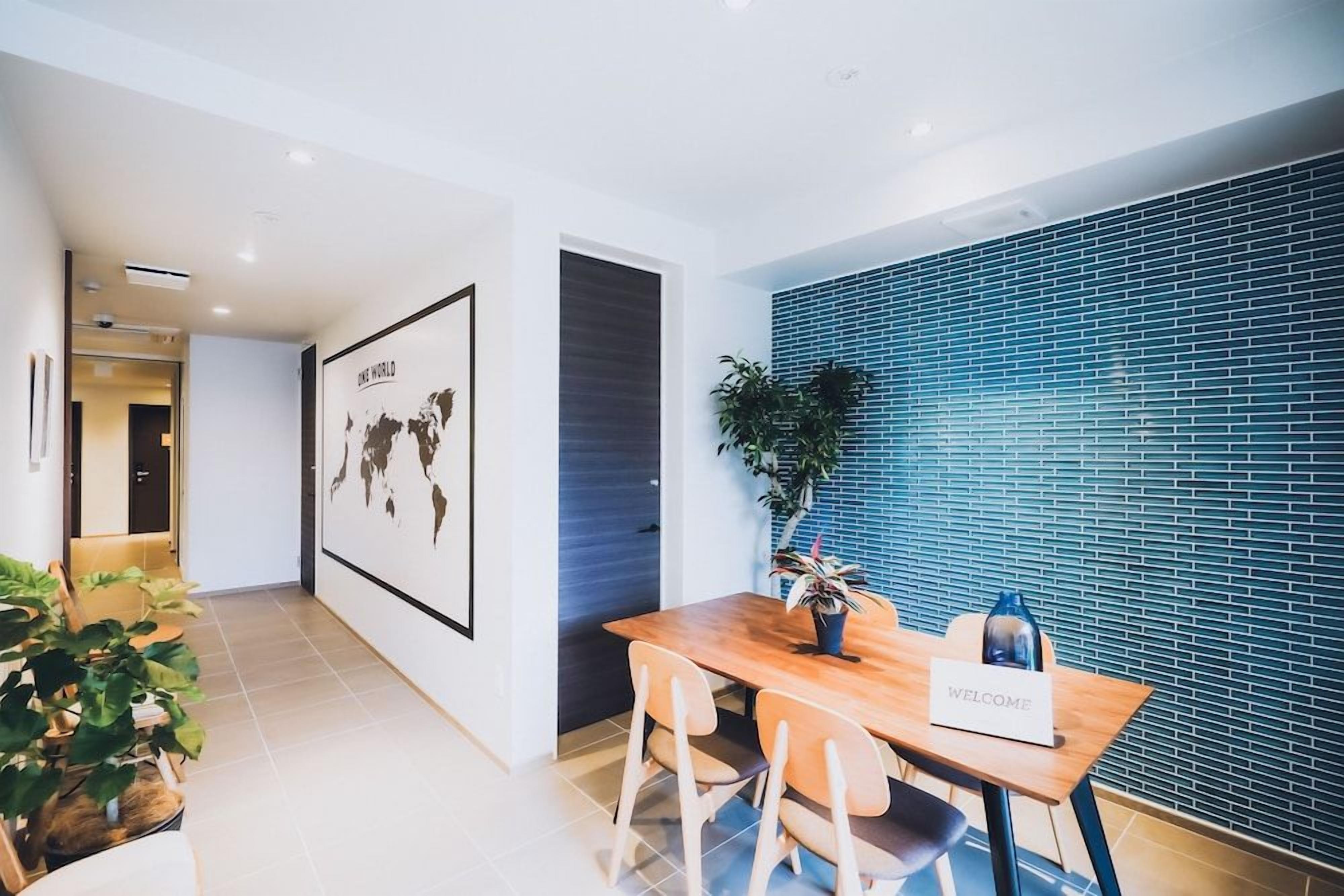 Un hall d’hôtel moderne avec un comptoir d’accueil en bois, une carte du monde accrochée au mur et un mur recouvert de carreaux bleus.