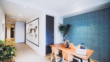Un hall d’hôtel moderne avec un comptoir d’accueil en bois, une carte du monde accrochée au mur et un mur recouvert de carreaux bleus.