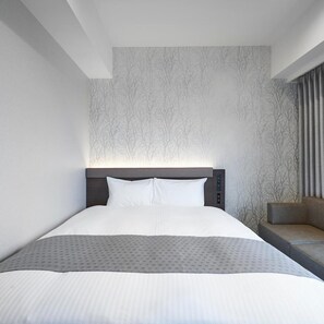 Ein modernes Hotelzimmer mit einem großen Bett, einer Couch und einer Wand mit Muster.