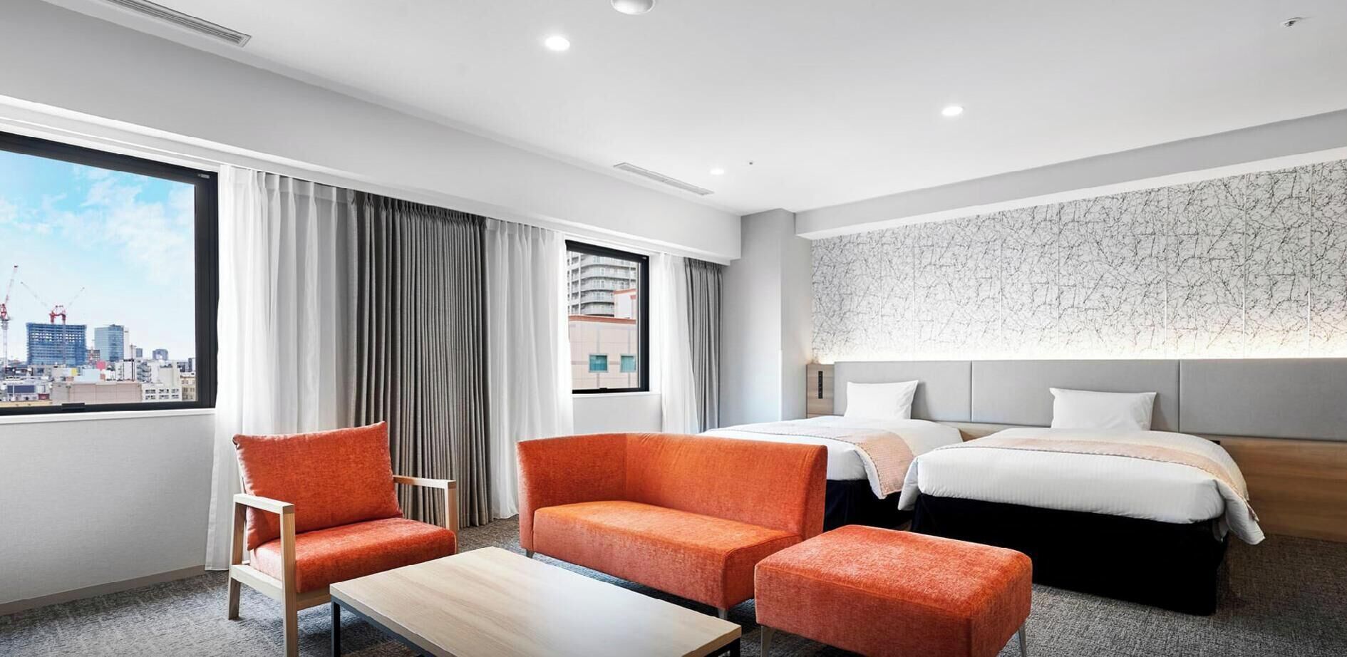 Ein Hotelzimmer mit Blick auf die Stadt, mit zwei Betten, einem Sofa, einem Couchtisch und einer Wand mit Muster.