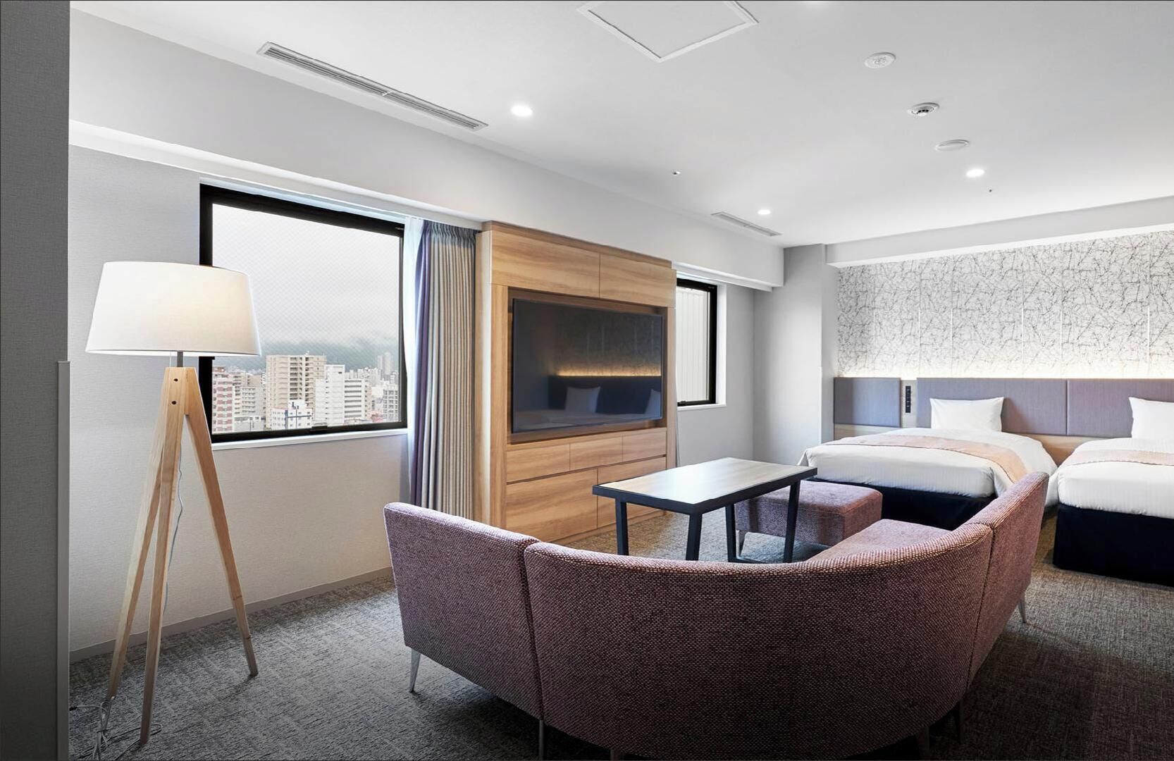 A hotel room with a city view, a sofa, a small table, a TV, and a bed.