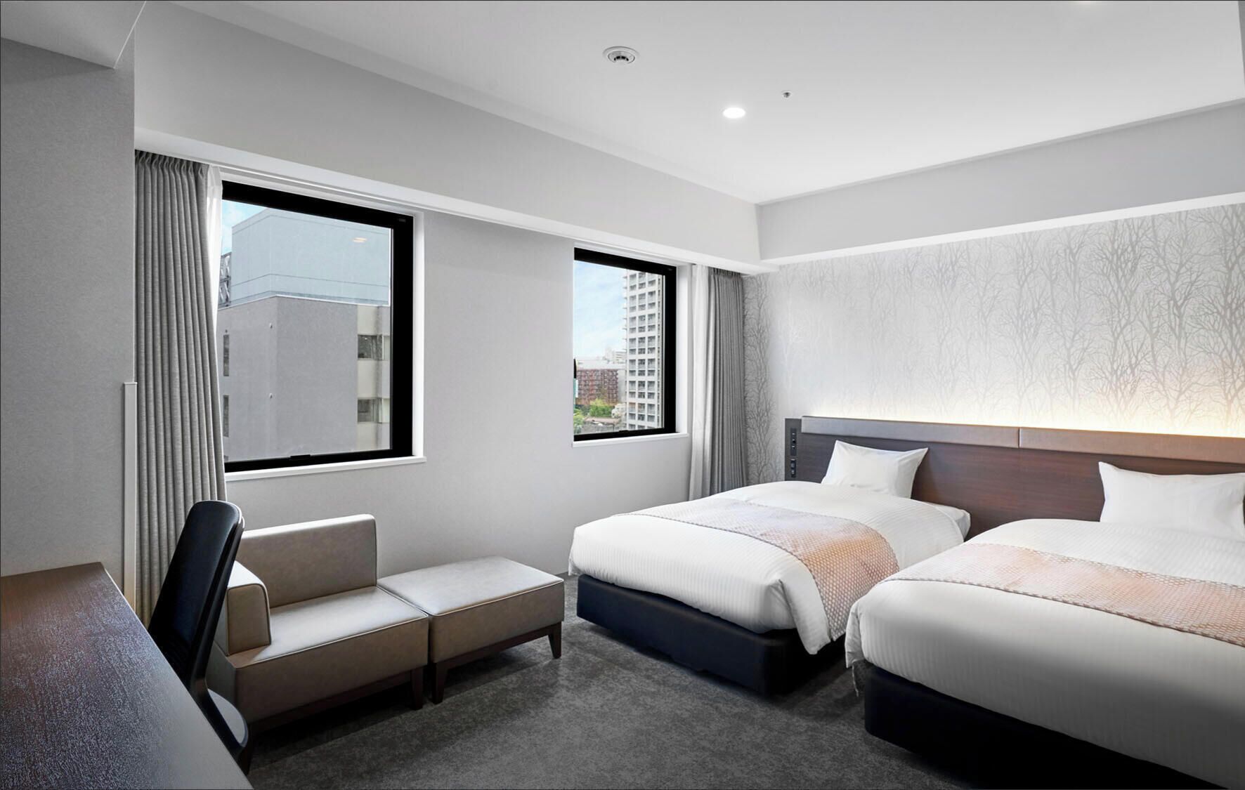 A hotel room with two beds, a desk, and a chair.
