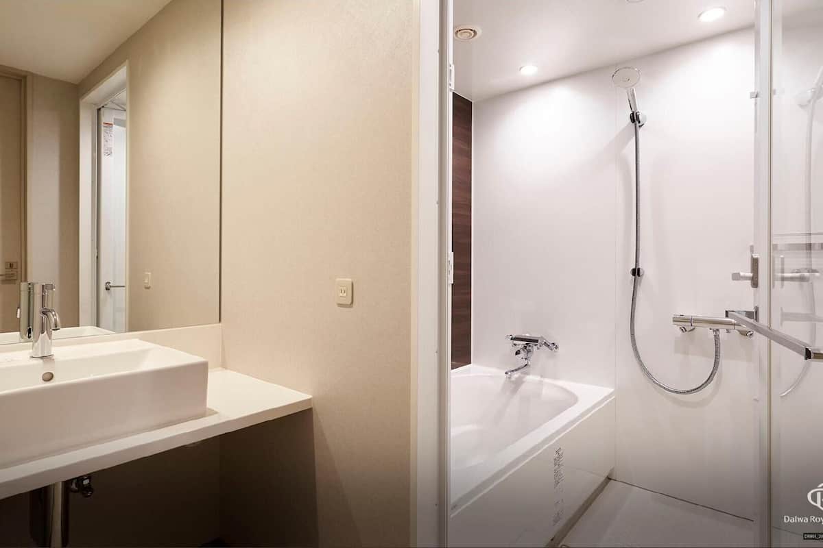 A modern bathroom with a large mirror, a sink, a shower with a glass door, and a bathtub.