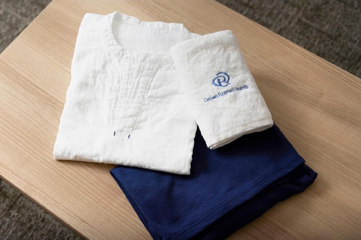 A white shirt with a logo and a folded blue garment on a wooden table.