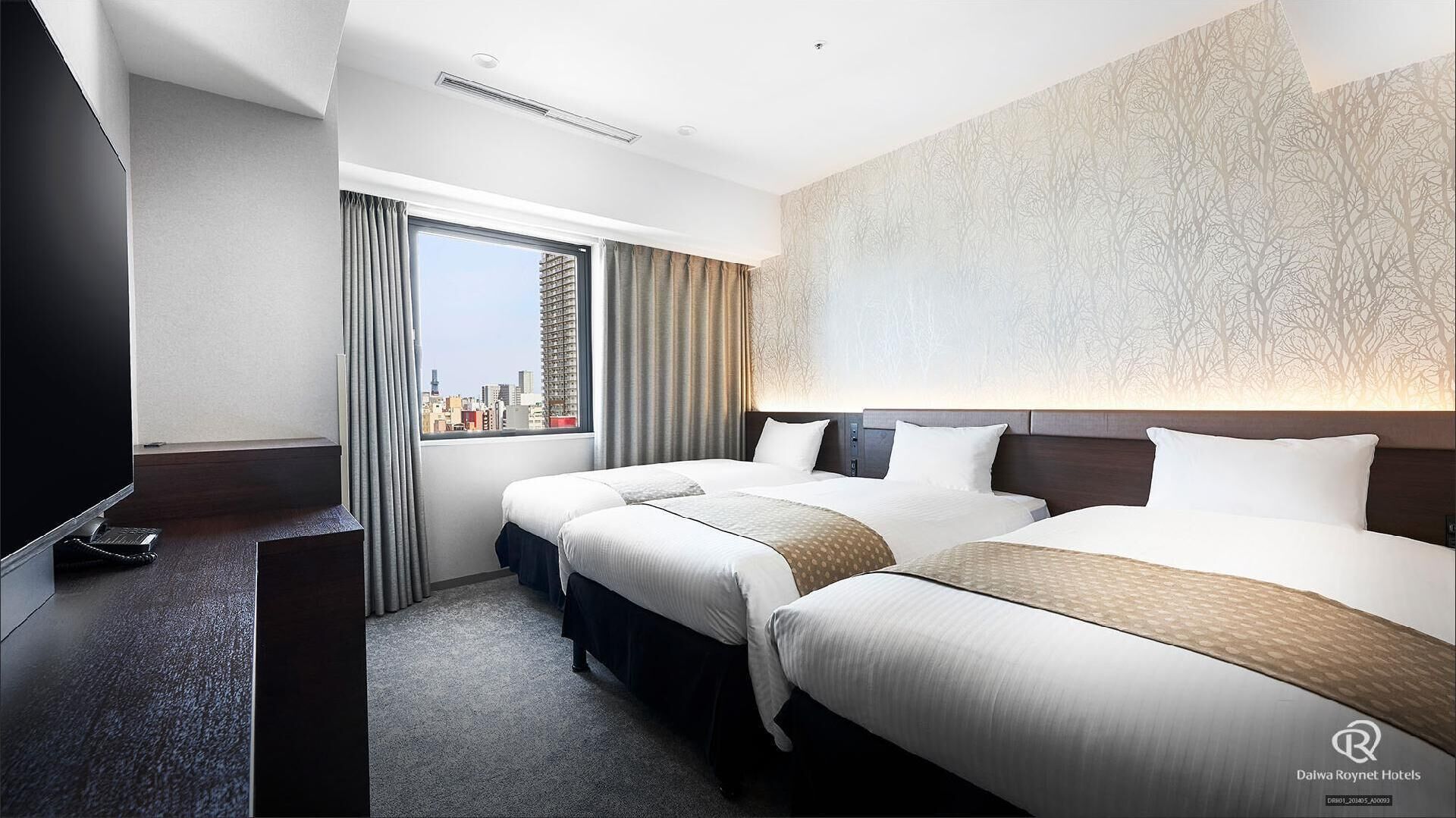 A hotel room with two beds, a TV, a desk, and a large window with a city view.