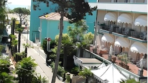 A multi-story building with a balcony on the upper floor, surrounded by trees and a clear sky. - Villa Roma (Caorle)