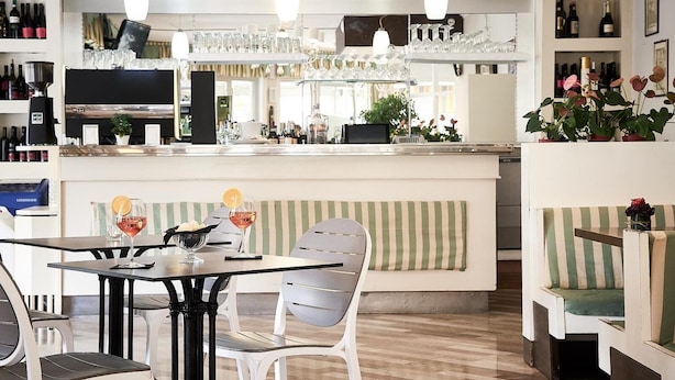 A bar area with a counter, seating, and a variety of bottles and glasses. - Villa Roma (Caorle)