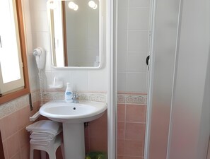 A bathroom with a white sink, a mirror, a towel rack, and a shower area. - Villa Roma (Caorle)
