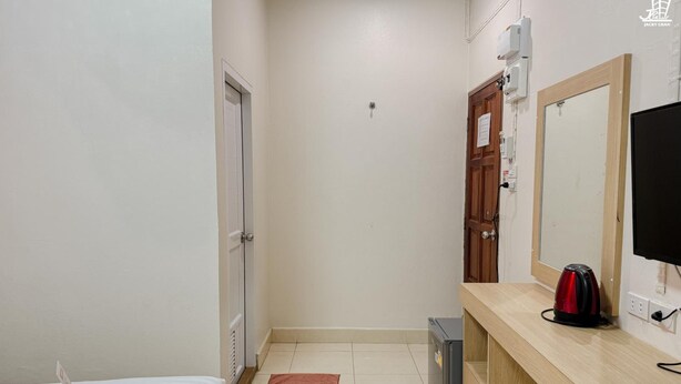 A hotel room with a bed, a small rug, a TV, a kettle, and a refrigerator. - Jacky Chan Hotel (Betong)