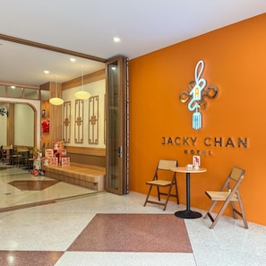 Entrada de hotel com design moderno, balcão de recepção e área de estar.