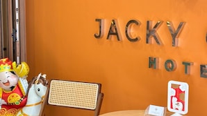 A hotel reception area with a round wooden table, a wicker chair, and a decorative figure. - Jacky Chan Hotel (Betong)
